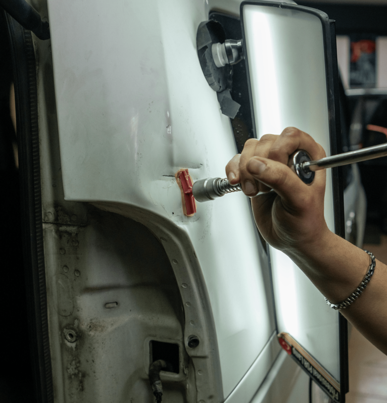 Reparación de abolladura en puerta de coche blanca en taller de chapa y pintura